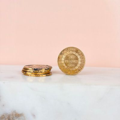 a gold coin sitting next to a stack of gold coins