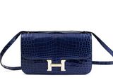 a blue handbag with a gold h logo on the front