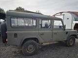 a grey land rover parked in a lot with a trailer in the background
