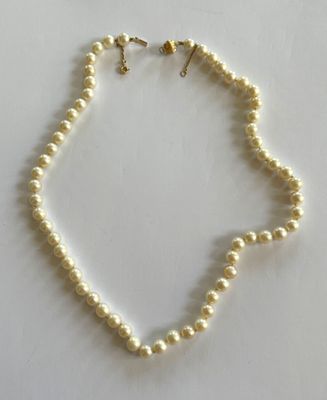 un collier de perles blanches posé sur une surface blanche