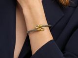 a woman wearing a black blazer and a gold bracelet