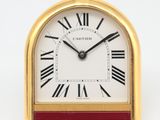 une image représentant une horloge dorée et rouge avec des chiffres romains