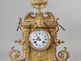 a gold clock with a bird on top of it