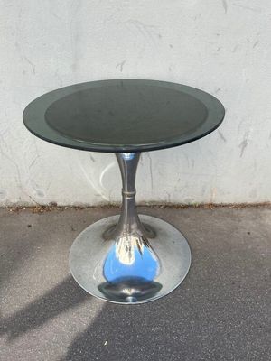 a glass table with a black top on a concrete floor