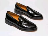 pair of black loafers on a white surface with a white background