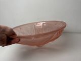 a person holding a pink glass bowl on a white surface