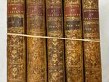 six vieux livres sont empilés sur une surface blanche