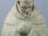 statue of a man sitting on a stool with his hands clasped