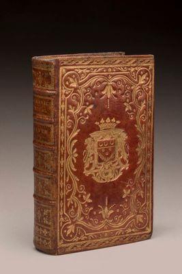 an old book with a gold and red cover on it