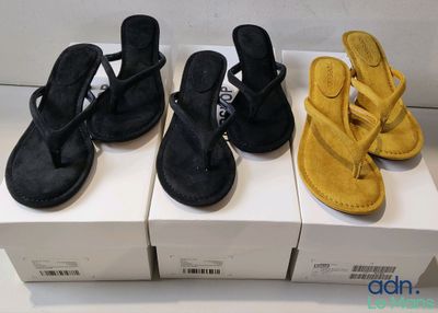 trois paires de sandales noires et jaunes posées sur des cartons