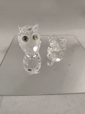 crystal figurines of a cat and an owl sitting on a glass table