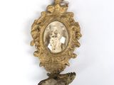 un cadre doré sur lequel figure le portrait d'une femme et d'un oiseau