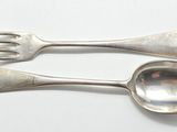 deux cuillères et une fourchette en argent sur une surface blanche