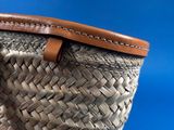 someone is holding a straw bag with a leather handle