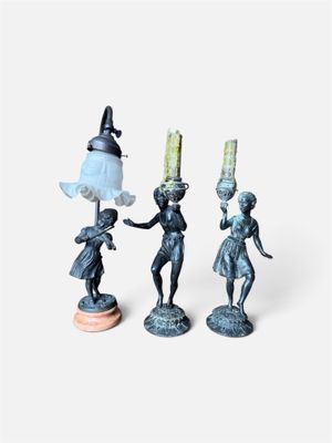 trois figurines représentant une femme tenant une lampe et un homme tenant une lampe
