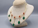 un collier composé de perles vertes et rouges, présenté sur un mannequin