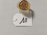 un gros plan d'une bague en or ornée d'une petite fleur