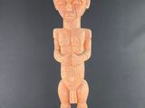une statue en bois représentant un homme debout sur une surface noire