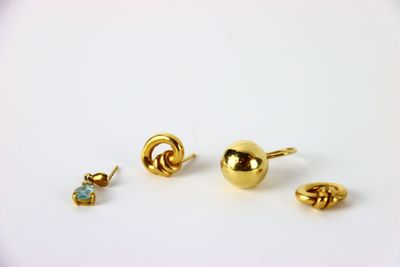 trois paires de boucles d'oreilles en or posées sur une surface blanche, sur fond blanc