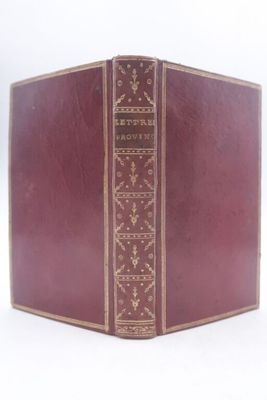 un vieux livre à la couverture rouge posé sur une surface blanche