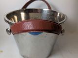 a metal bucket with a leather handle on a table