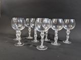 six clear wine glasses lined up in a row on a black background