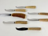 several knives and a fork are lined up on a white surface