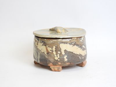 a small pot with a lid sitting on a white surface