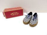 une paire de Slip-On Vans à carreaux à côté d'une boîte rouge