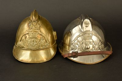 une paire de casques de pompier en laiton sur fond noir, avec un fond noir