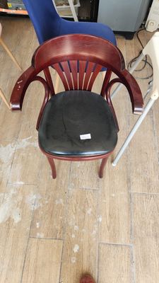 a wooden chair with a black seat in the middle of a room