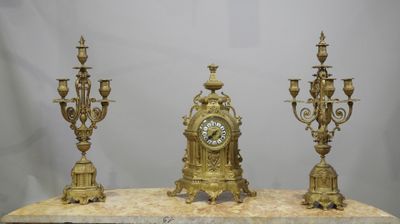 three gold colored clocks sitting on top of a marble table