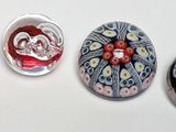 four glass magnets with different designs on them on a white surface
