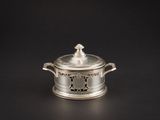 une cocotte ancienne en métal argenté avec un couvercle, sur fond noir