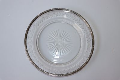 une assiette en verre bordée d'argent posée sur une table blanche