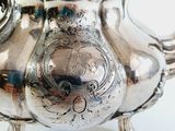 a silver tea pot sitting on a stand on a table