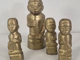 three gold figurines of children sitting on a white surface