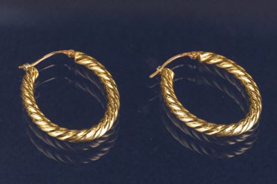 une paire de boucles d'oreilles en or sur une surface noire