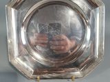 une image représentant une assiette en argent sur laquelle figure l'image d'un homme tenant un appareil photo