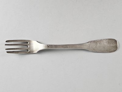 une fourchette en argent posée sur une surface blanche, avec une fourchette au milieu de la fourchette