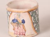 a small cup with a picture of a woman holding a basket