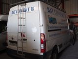 une camionnette blanche garée dans un garage, avec une échelle à l'arrière