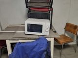 a microwave sitting on top of a table next to a chair