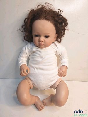 a baby doll that is sitting on a white surface