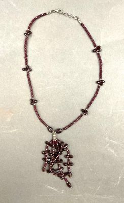 a close up of a necklace with beads on a white surface