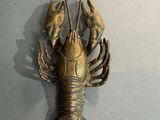 un homard en métal accroché au mur, à côté d'une lampe