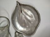 a silver plate with a leaf on it next to a purse