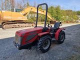 une photo d'un tracteur rouge garé sur un terrain en gravier