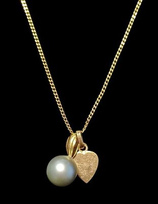 un pendentif en forme de cœur en or orné d'une perle, monté sur une chaîne