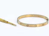 bracelet en or orné de la lettre « e » et d'un stylo sur un fond blanc